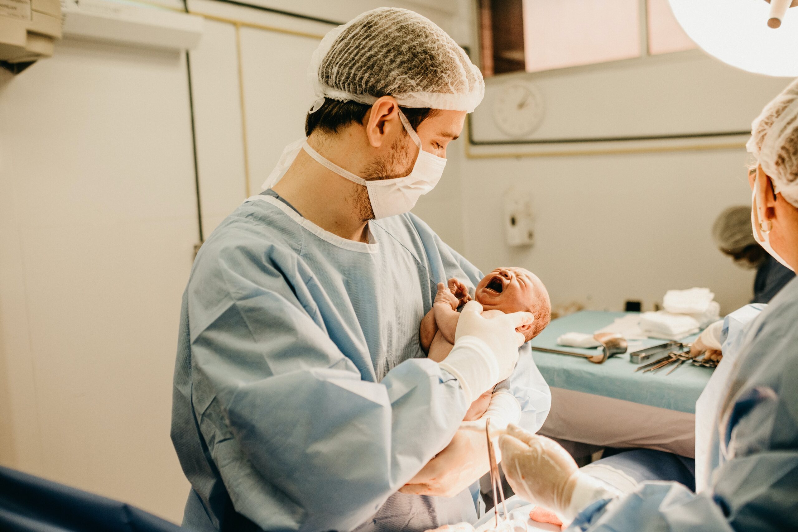 lekarz trzymający noworodka na rękach